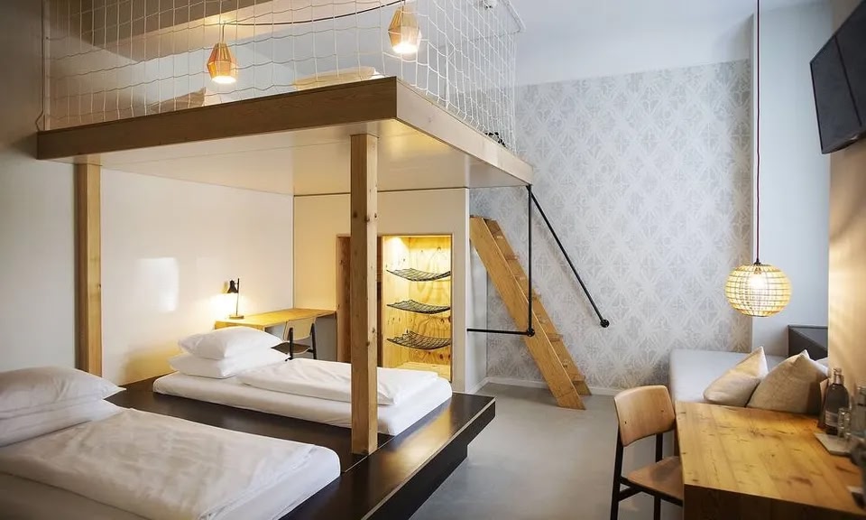 Una habitación en el Hotel Michelberger con dos camas individuales y una escalera que conduce a un entrepiso con más espacio para camas
