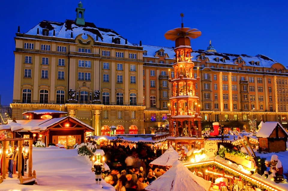Snow covers the tiny rooftops of stalls at the Striezelmarkt in Dresden, and the Christmas tower stands brightly in the centre.