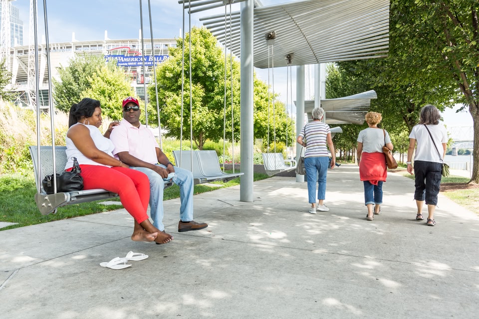 People relaxing on a bench, as a group walk past, in The Banks.