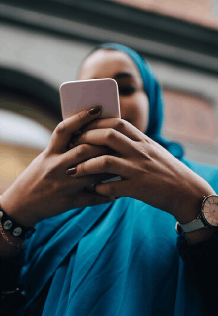 A close-up of a woman using a white mobile phone.