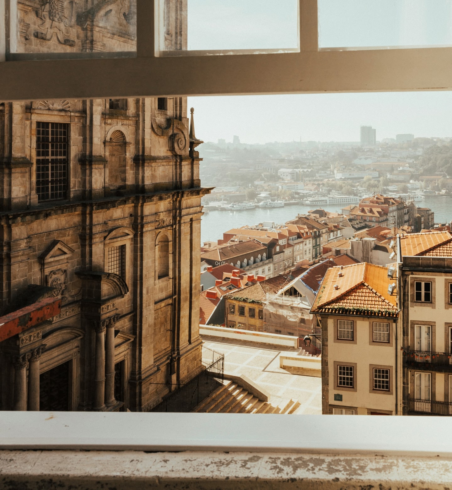 Uma vista dos telhados vermelhos e do rio Douro através da moldura de uma janela de pedra em Porto, Portugal.