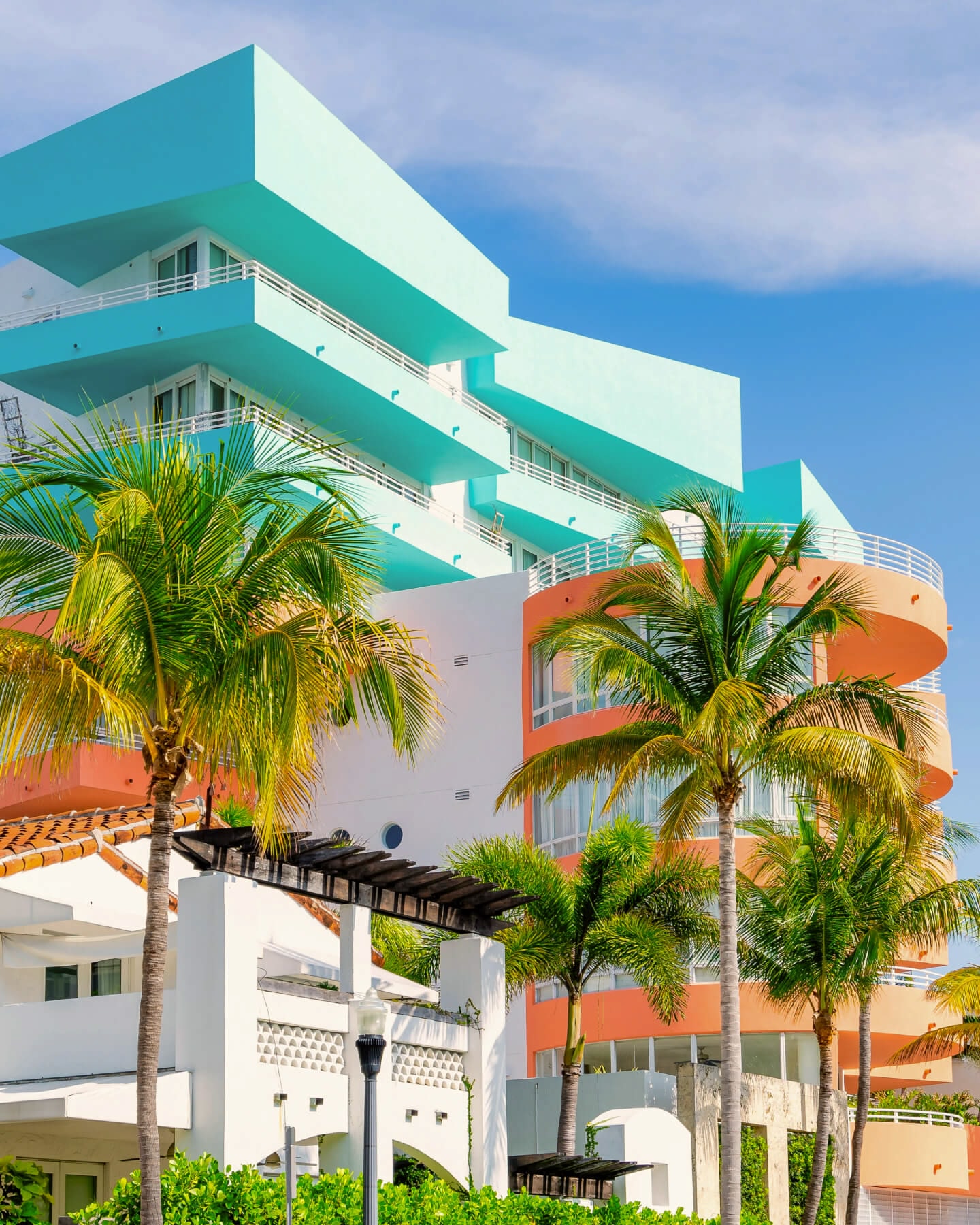 Blue, peach and white coloured Art Deco-style building with palm trees in the foreground
