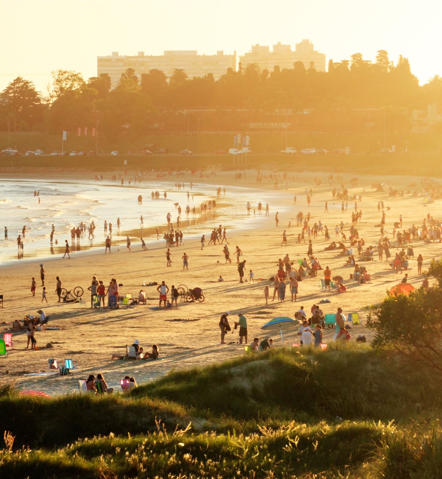 La gente disfruta de la playa mientras la cálida luz del atardecer baña la costa cerca de Montevideo, Uruguay.