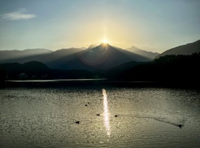 il sole che sorge sopra le montagne su un lago