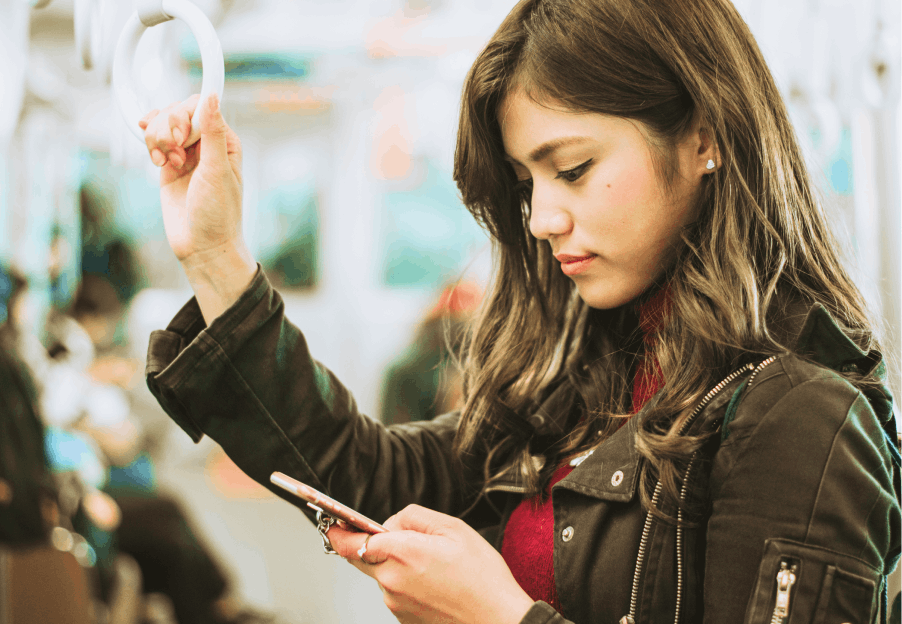 A woman checking the Skyscanner Tokyo travel guide on her phone while she rides on the Keisei Skyliner. 