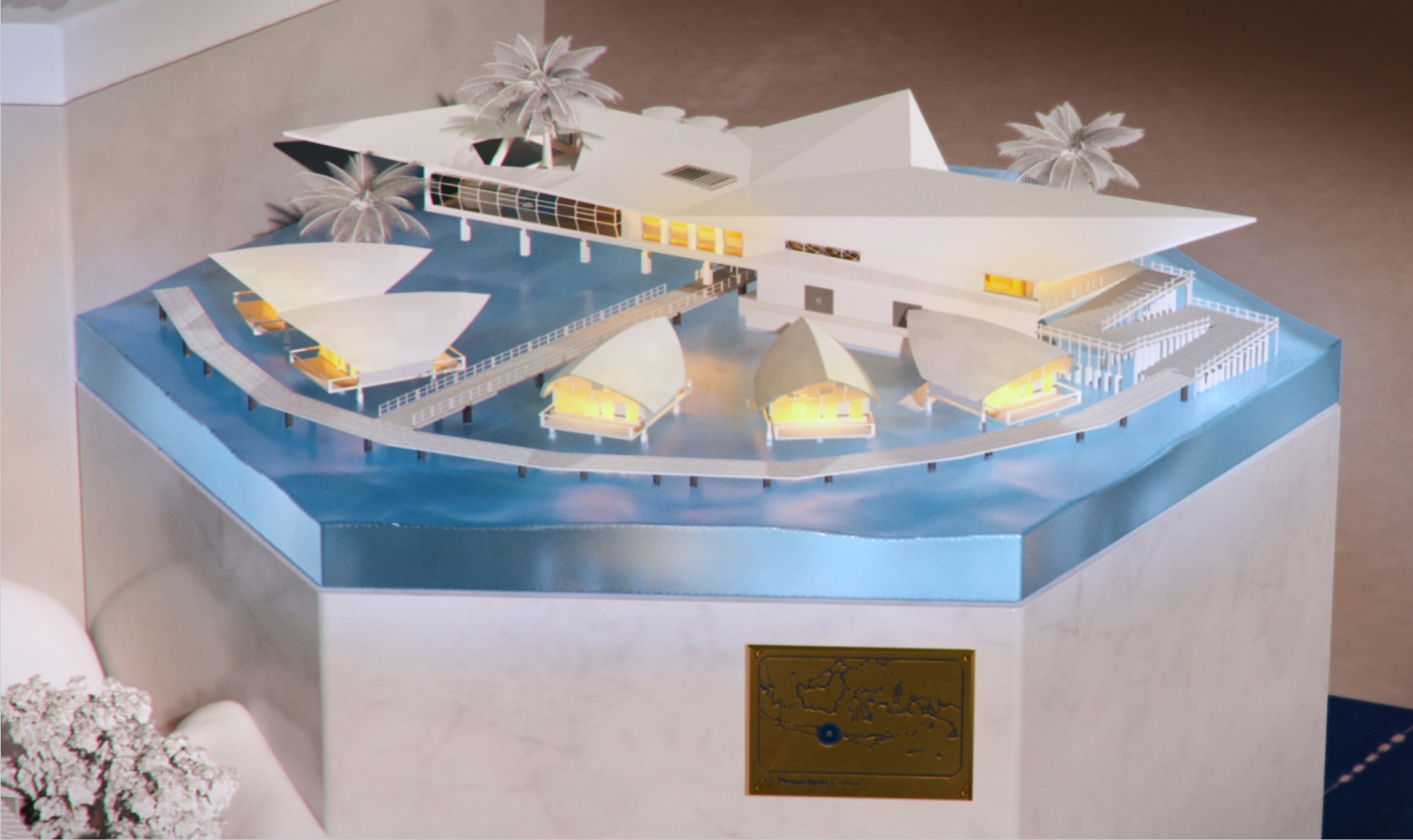 White and blue model of lit up Balinese-style water bungalows around a central hotel building