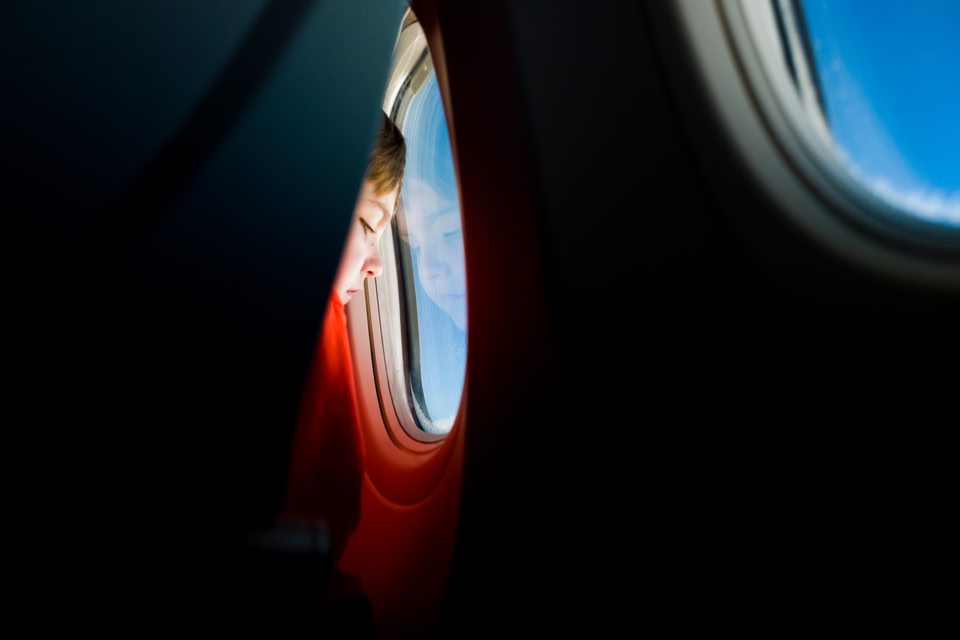 child looking out the window of a plane, view from the seat behind.