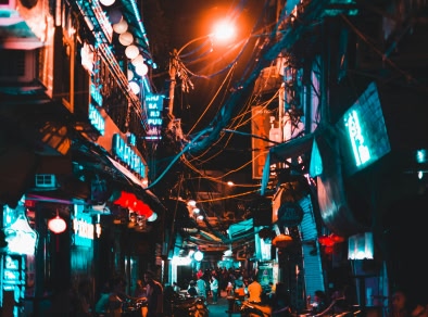 Imagen de una calle de Hanoi de noche, con una multitud bulliciosa y una iluminación atmosférica.