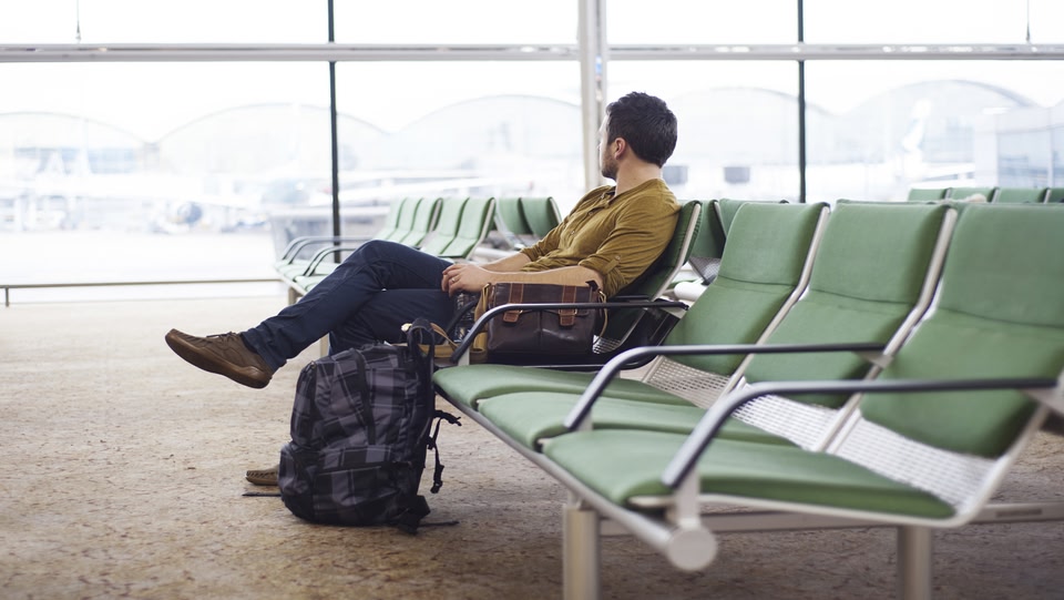 a man sat down on a row of chairs in an airport 