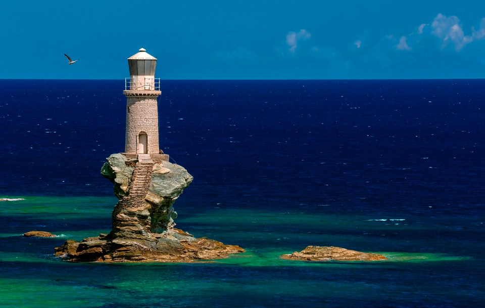 Faro Tourlitis - beautiful lighthouse perched on curved rock platform in Andros, Greece