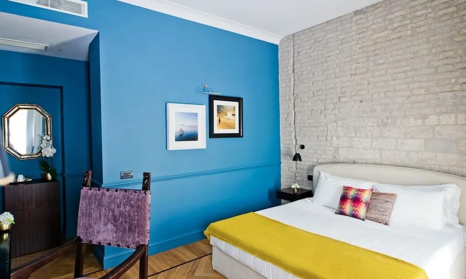 Una habitación del Hotel Fifteen Keys. Una pared está pintada de un azul vibrante y la otra es de ladrillo visto pintado de blanco.
