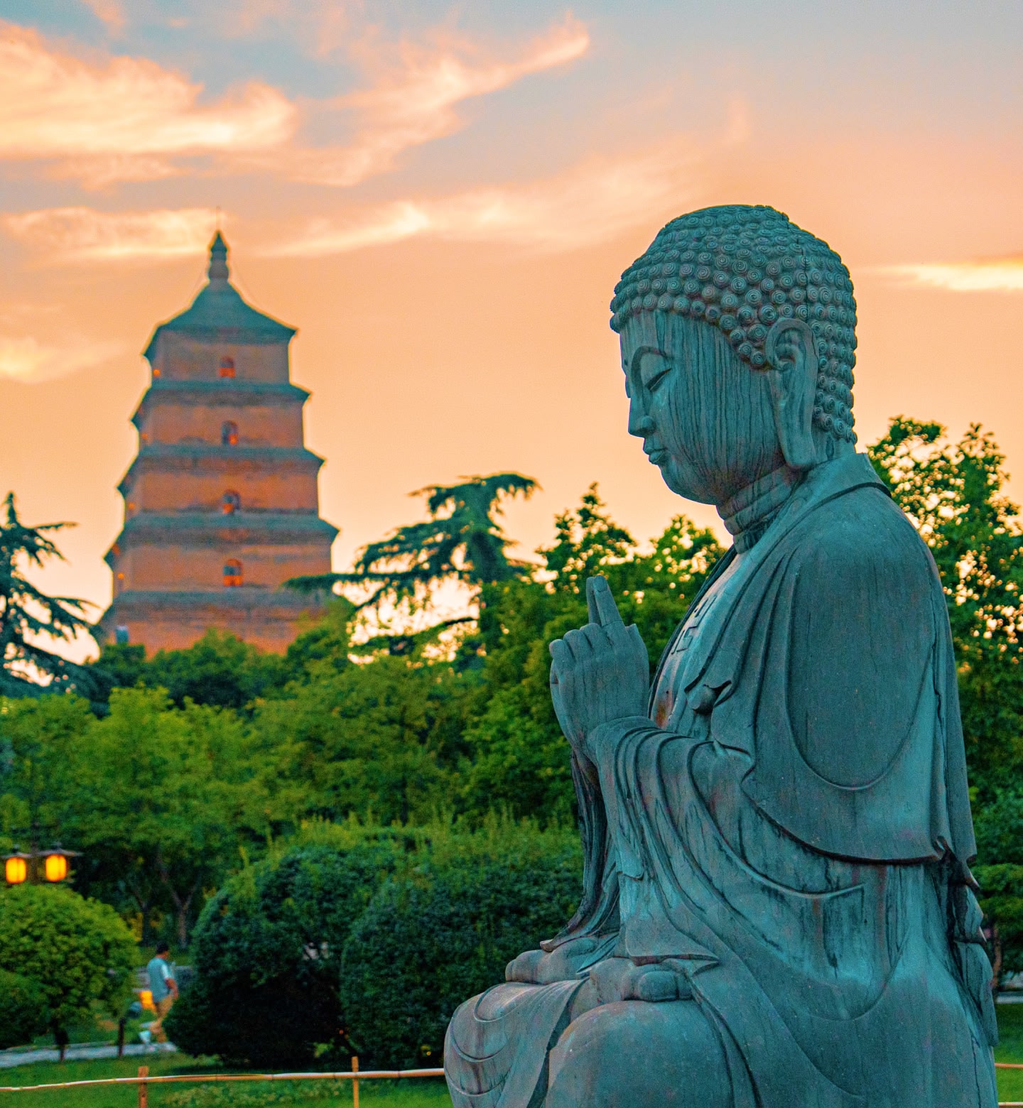 Una statua di Buddha al tramonto a Xi An, in Cina, con una pagoda che si erge sullo sfondo.