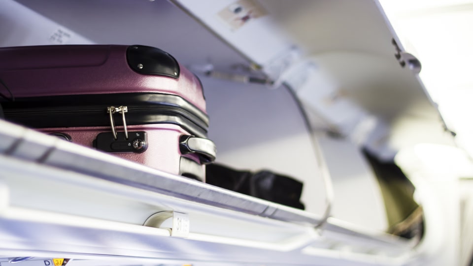 Handgepäck Koffer im Gepäckfach im Flugzeug verstaut