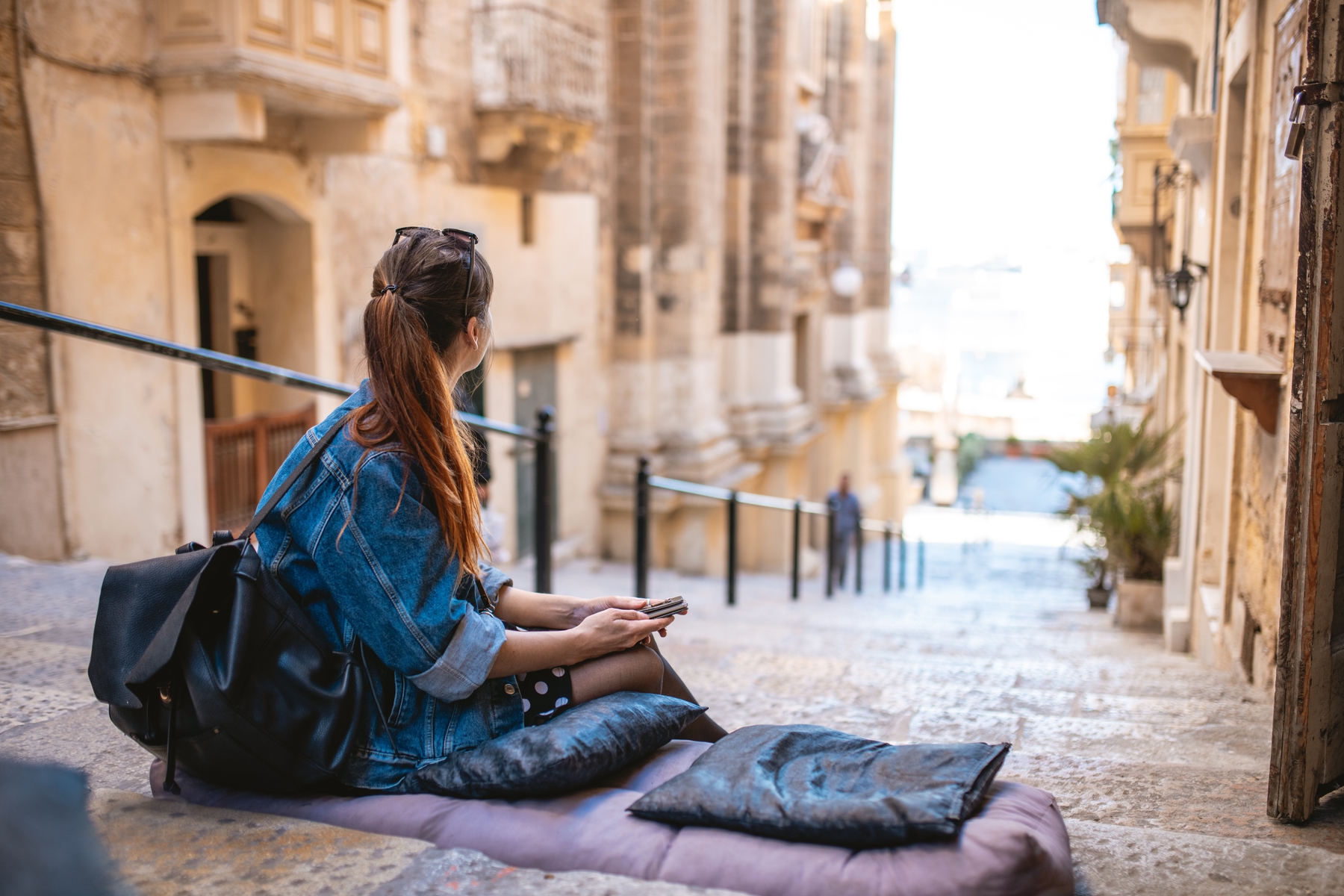 Young woman sitting outside ona flight of steps, checking her phone