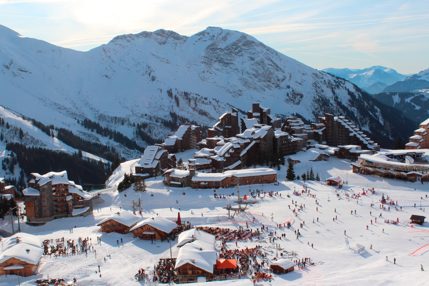 View of a busy but small ski resort from above, with a mountain in the background