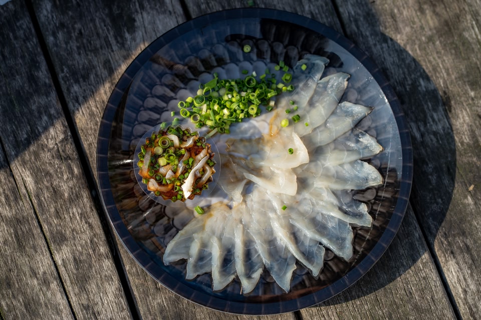 A plate of pearly white Fugu Pufferfish sashimi with chopped chives at Karatocho fish market in Shimomoseki Yamaguchi Prefecture Japan.