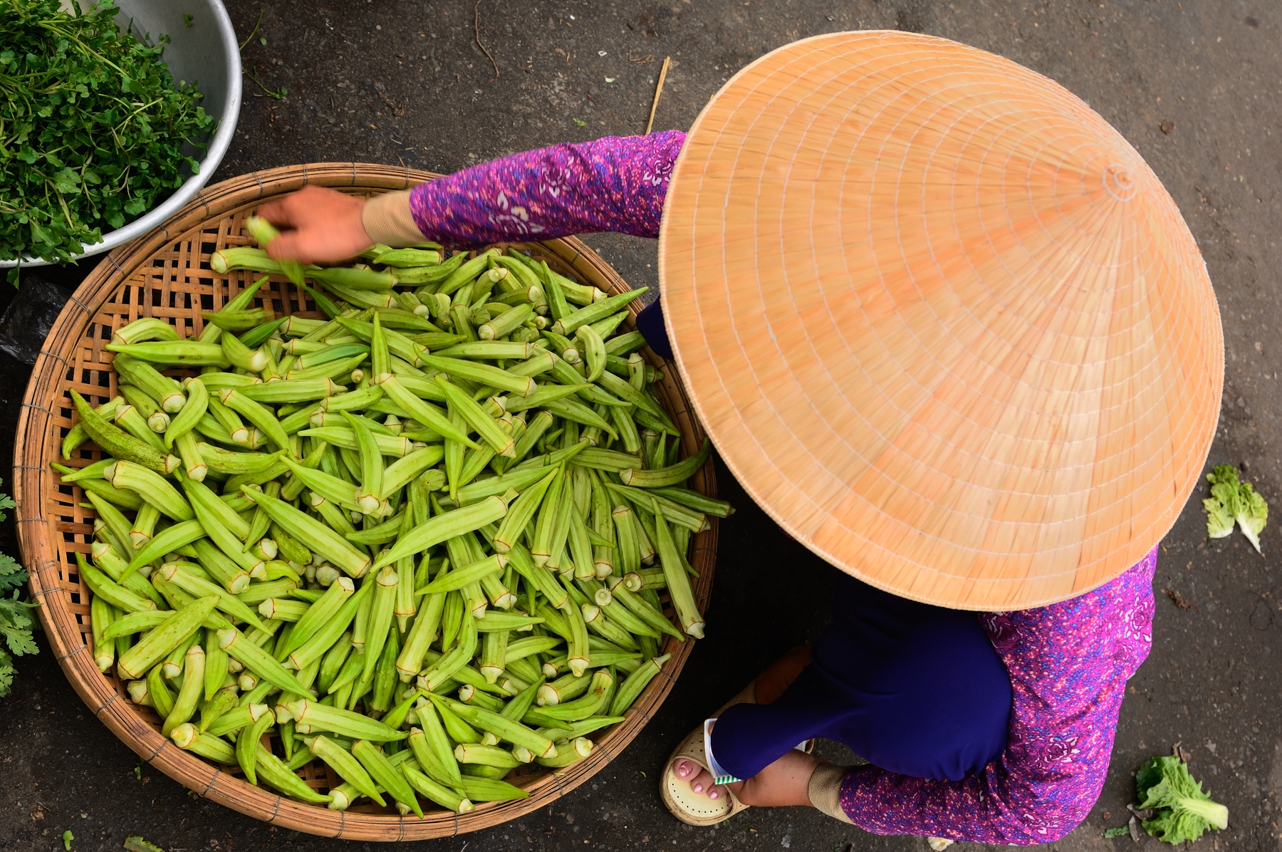 Vietnamese woman with bamboo hat selling veggies at a street market