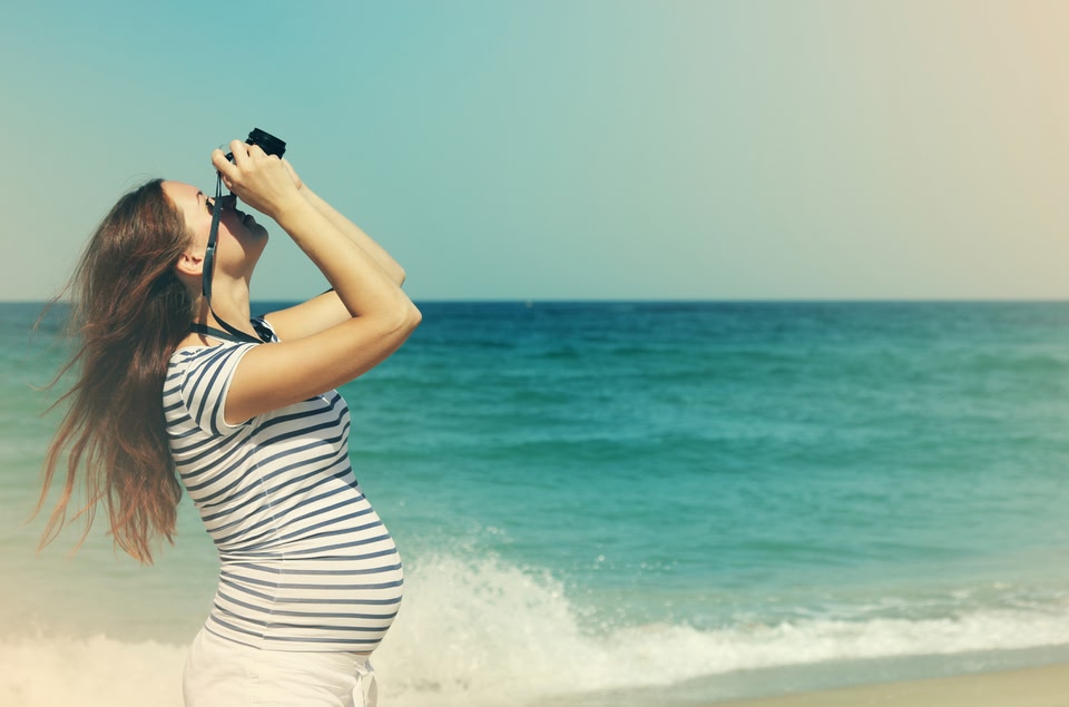 Woman by the sea looking up through binoculars
