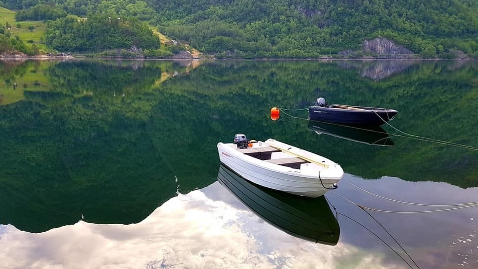 A two boats on a lake in Norway surrounded by green mountains.