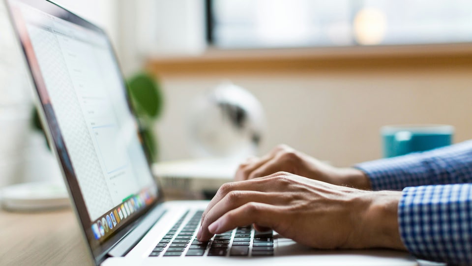 Hands typing on laptop keyboard