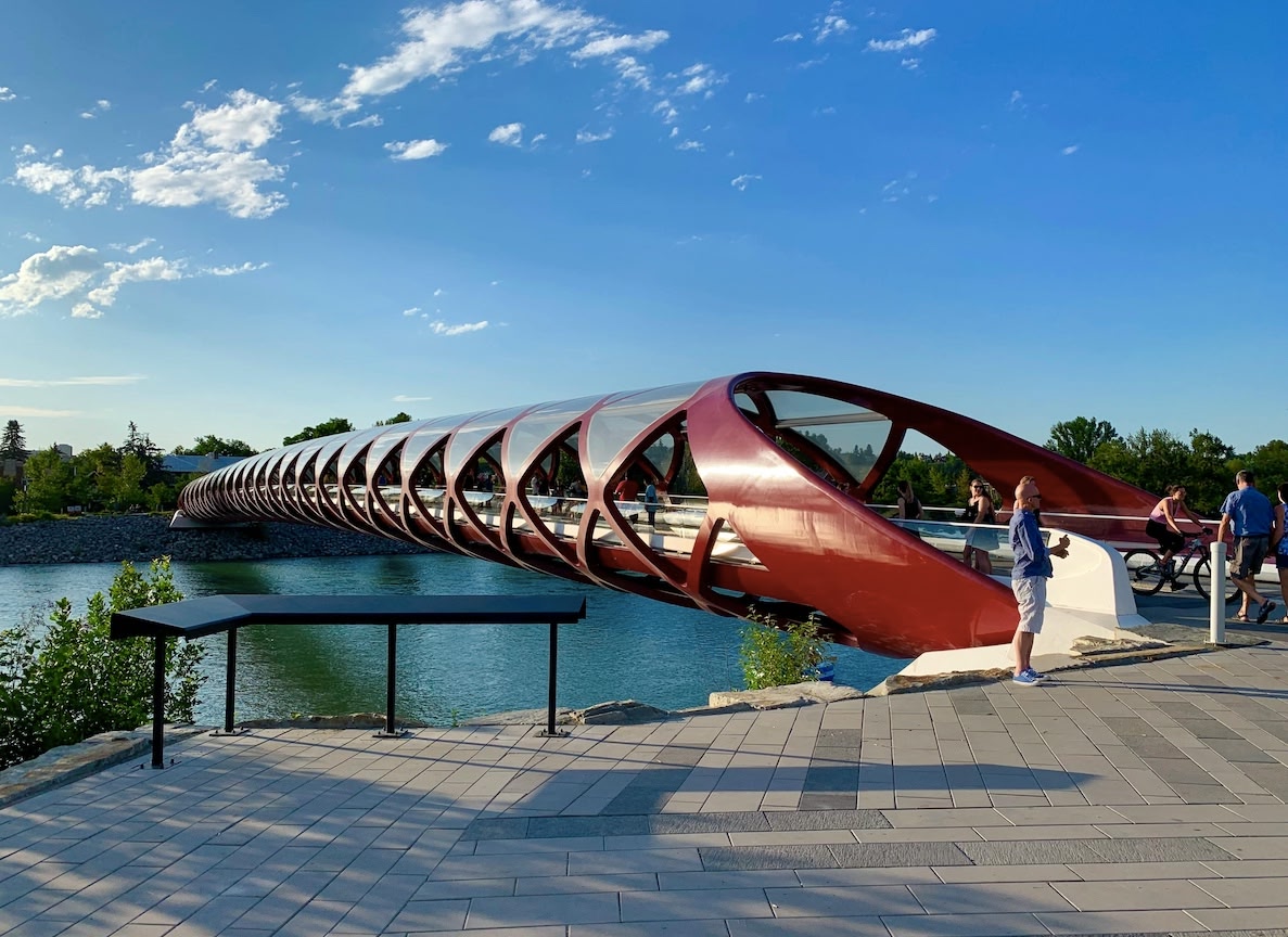 People in front of Calgary Peace Bridge, blue skies. Crossing this famous Calgary attraction is one of the top things to do in the city.