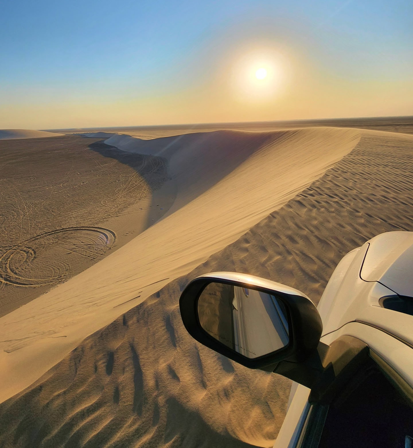A picture of rolling sand dunes stretching to the horizon taken from the window of a vehicle in Dammam, Saudi Arabia.