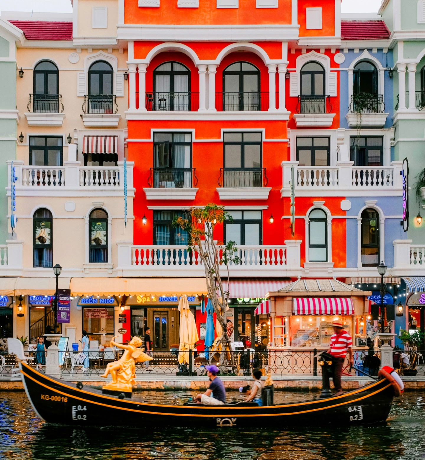 ベトナムのフーコック島、運河沿いの店やカフェのある色鮮やかな建物の前を通り過ぎるゴンドラ。