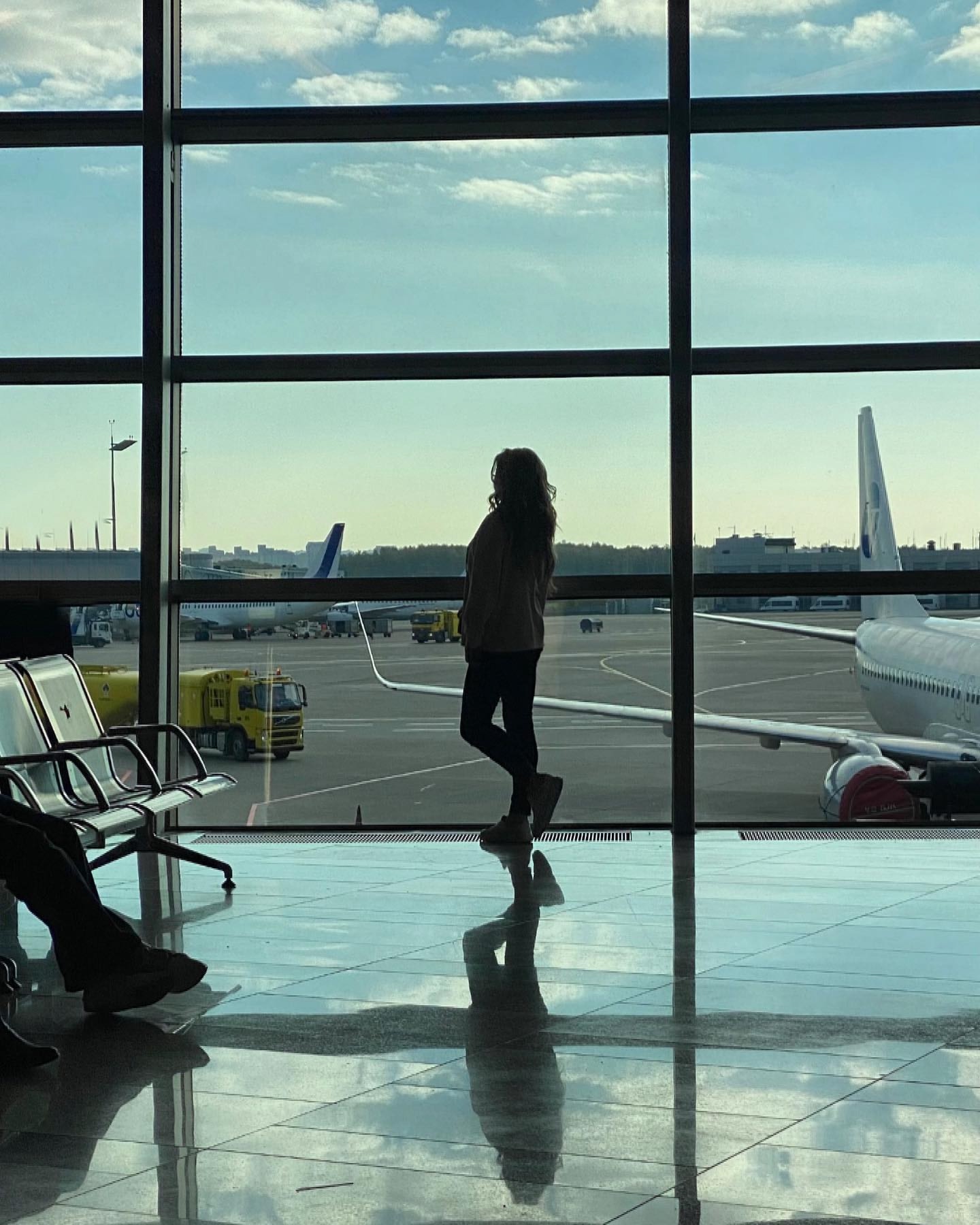 Frau am Flughafen schaut aufs Rollfeld
