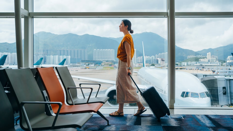 a woman walks through an airport terminal pulling her luggage.