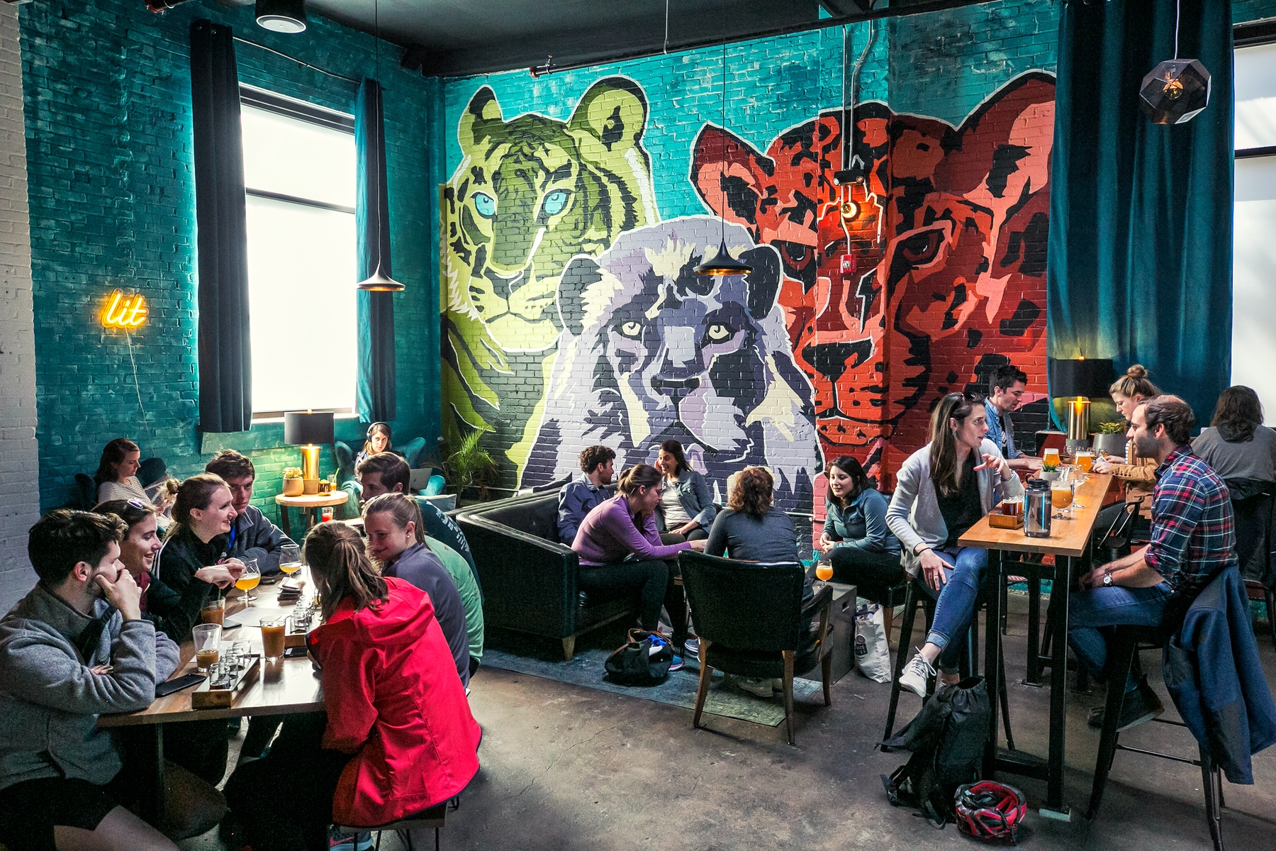 people sitting drinking and chatting inside Lamplighter Brewing Company, one of Boston's microbreweries. Graffiti in the background