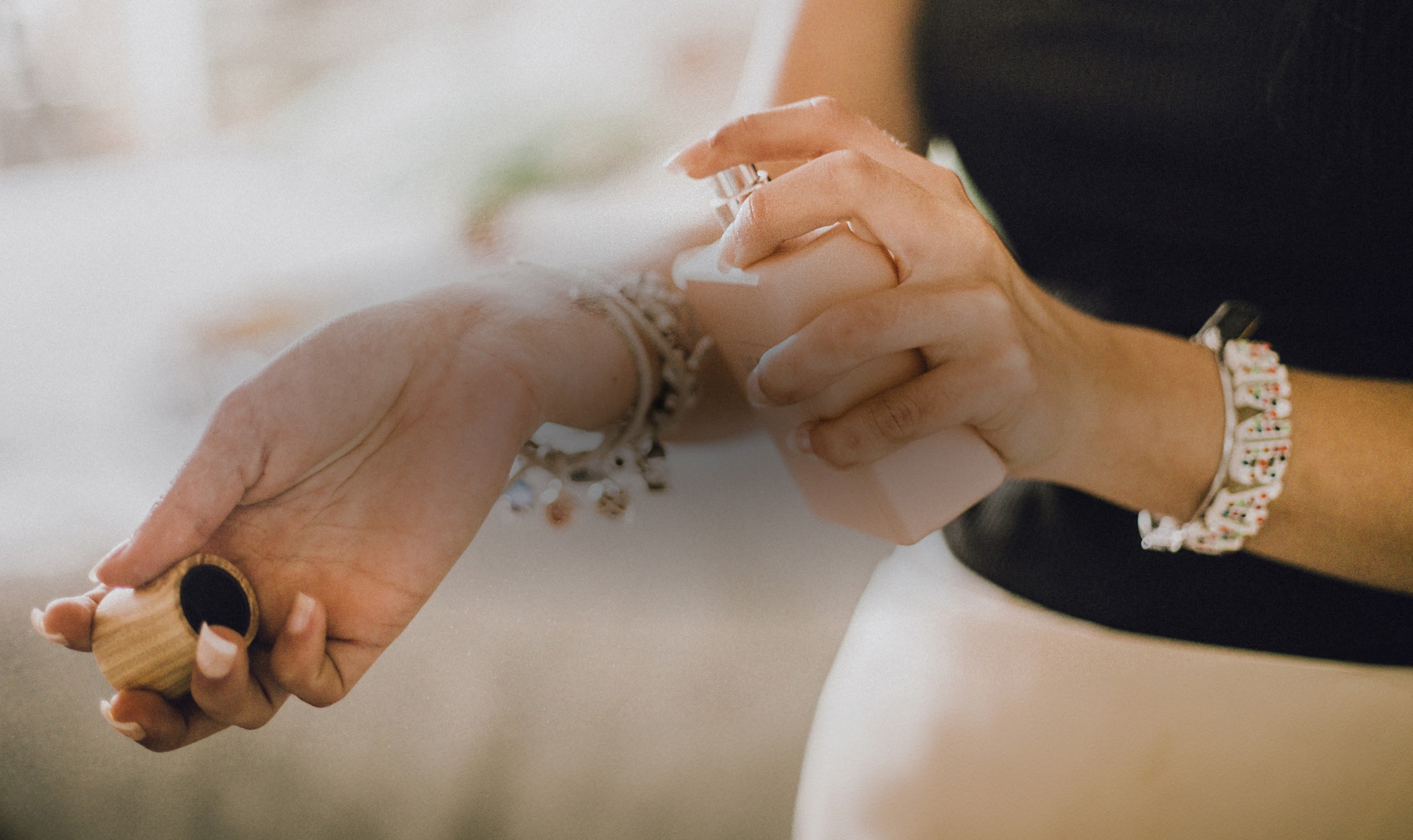 A close up of a woman spraying perfume on her wrist.