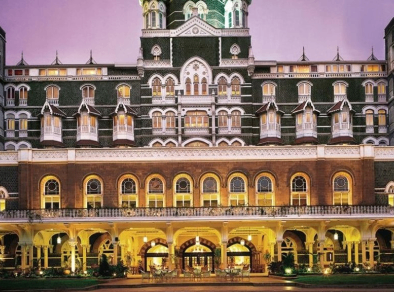 Exterior view of the iconic Taj Mahal Palace hotel, showcasing its grand architecture and majestic presence at night.