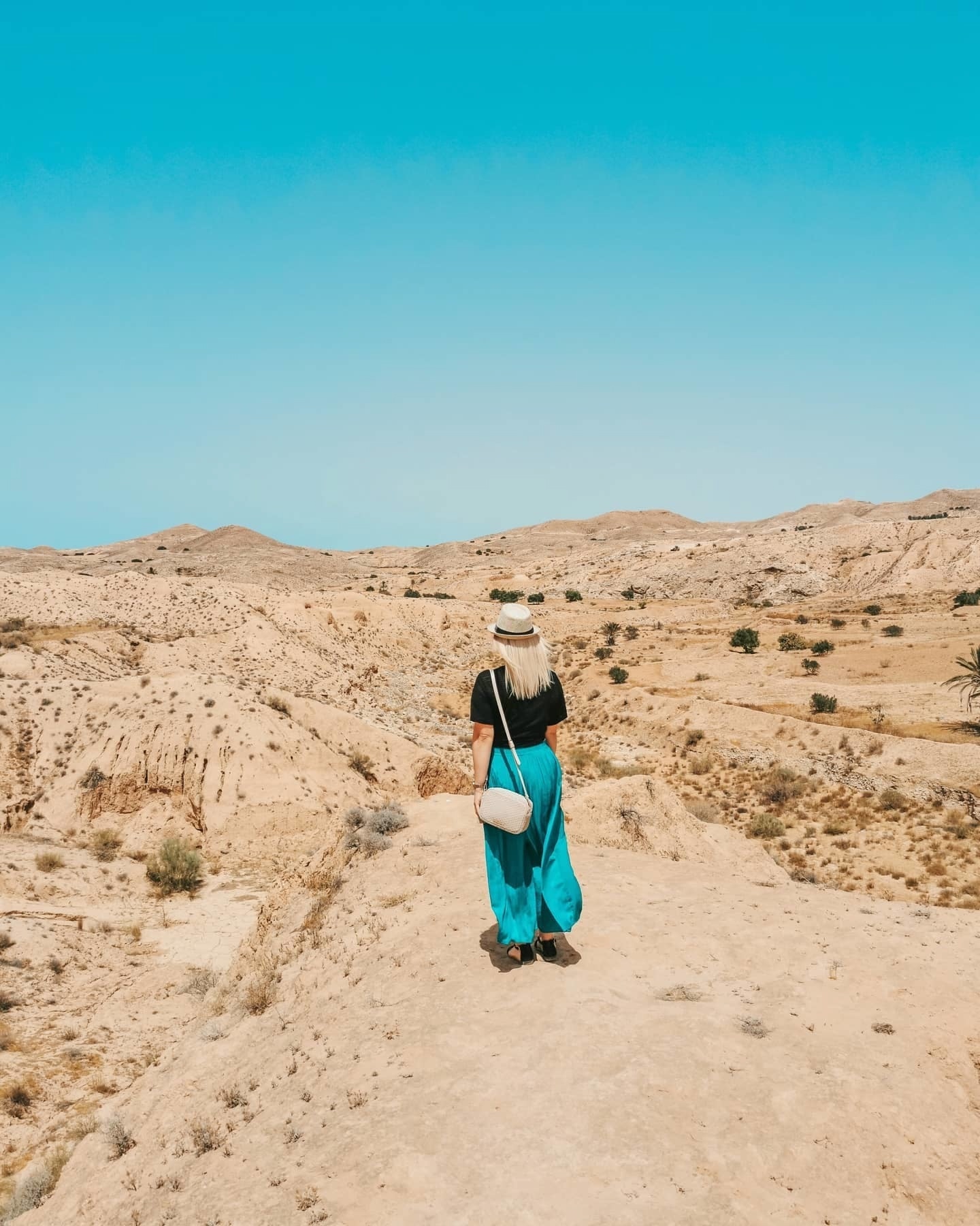 Eine Frau steht inmitten der Wüste in Tunesien