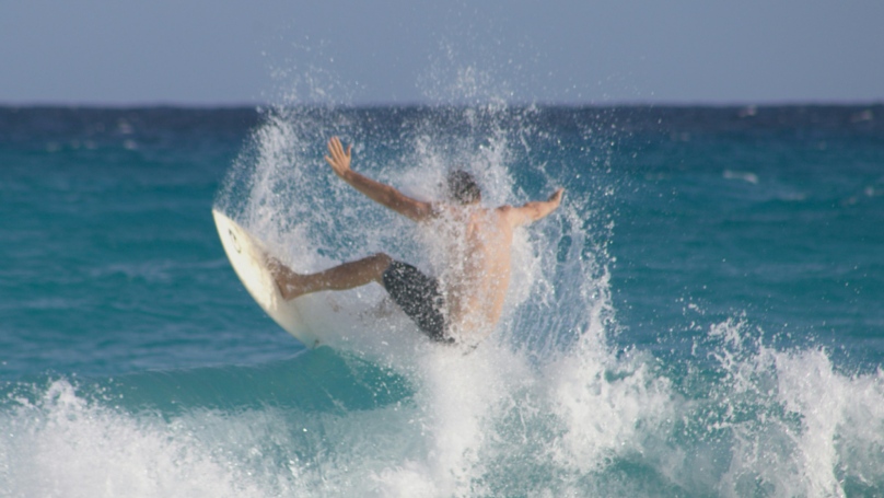 Uma pessoa surfando em Cancún durante o dia.