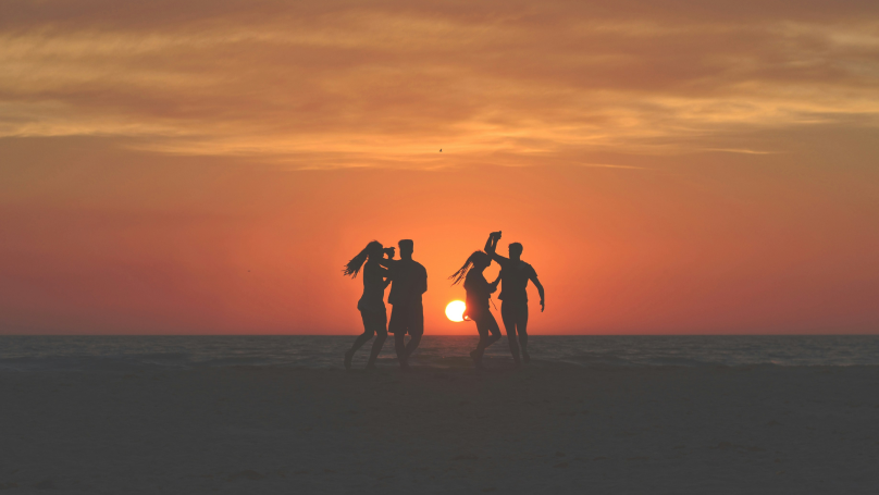 Four people dancing on a beach at sunset at the Playa Marlin