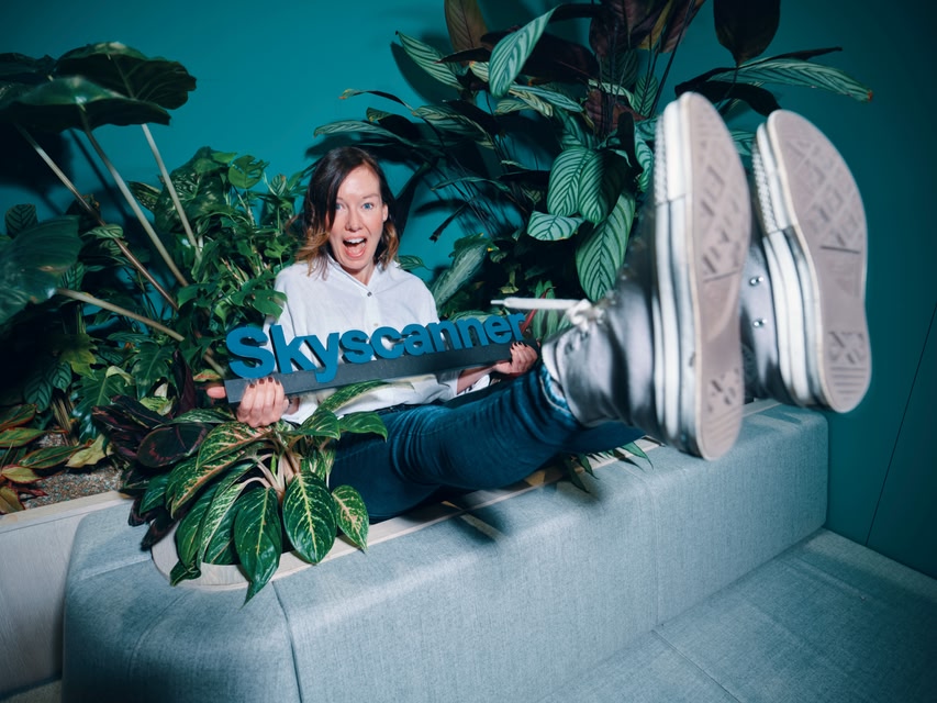 Team member holding up a skyscanner sign sitting in a planter