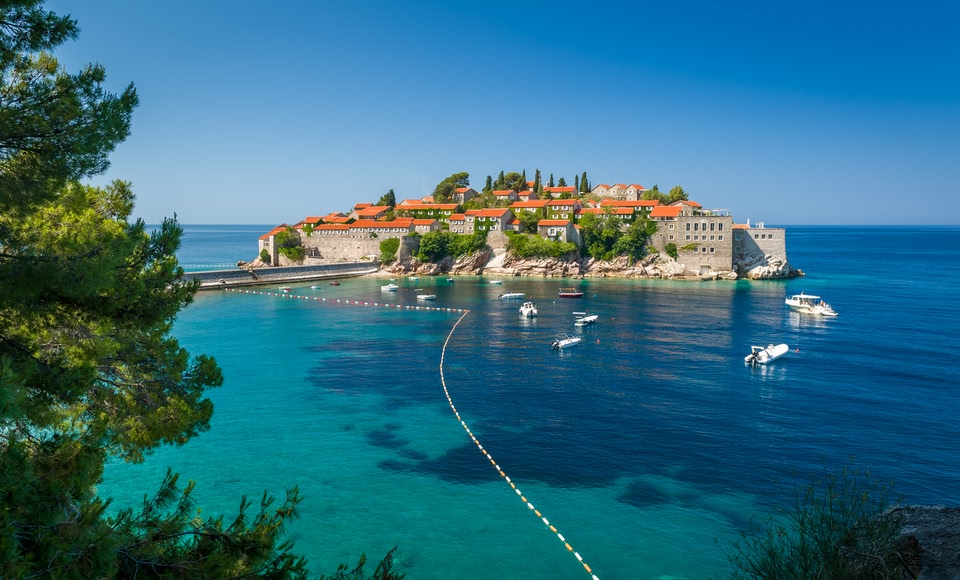 Aman Sveti Stefan, a private resort on an island off the coast of Montenegro. Shown here with some boats in the water.