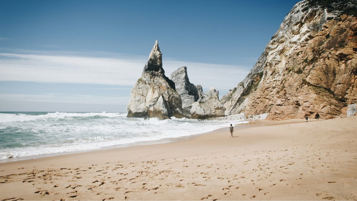 Une photo pittoresque d'une plage vide avec une superbe formation rocheuse en arrière-plan