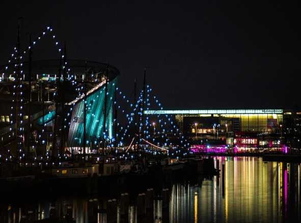 Amsterdam at night during the Museum Night event. Neon lights surround the museums on either side of the canal.