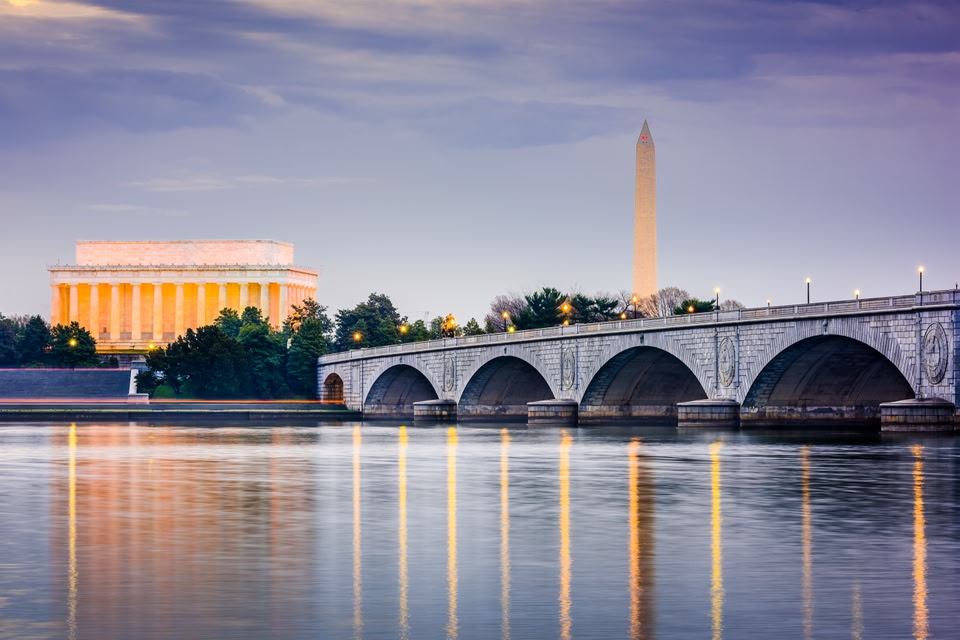 Sunset view of the Lincoln Memorial and Washington Monument illuminated behind the Arlington Memorial Bridge.