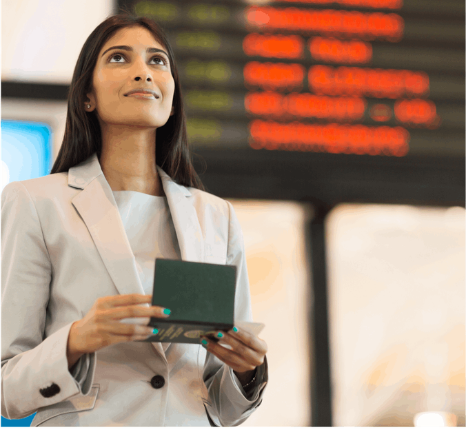 A confident woman stands in an airport, holding her passport with anticipation. Her gaze is directed upward, capturing the excitement of travel. In the background, a flights timetable is visible.