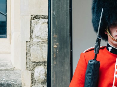 Une garde britannique se tient près d'un mur brun