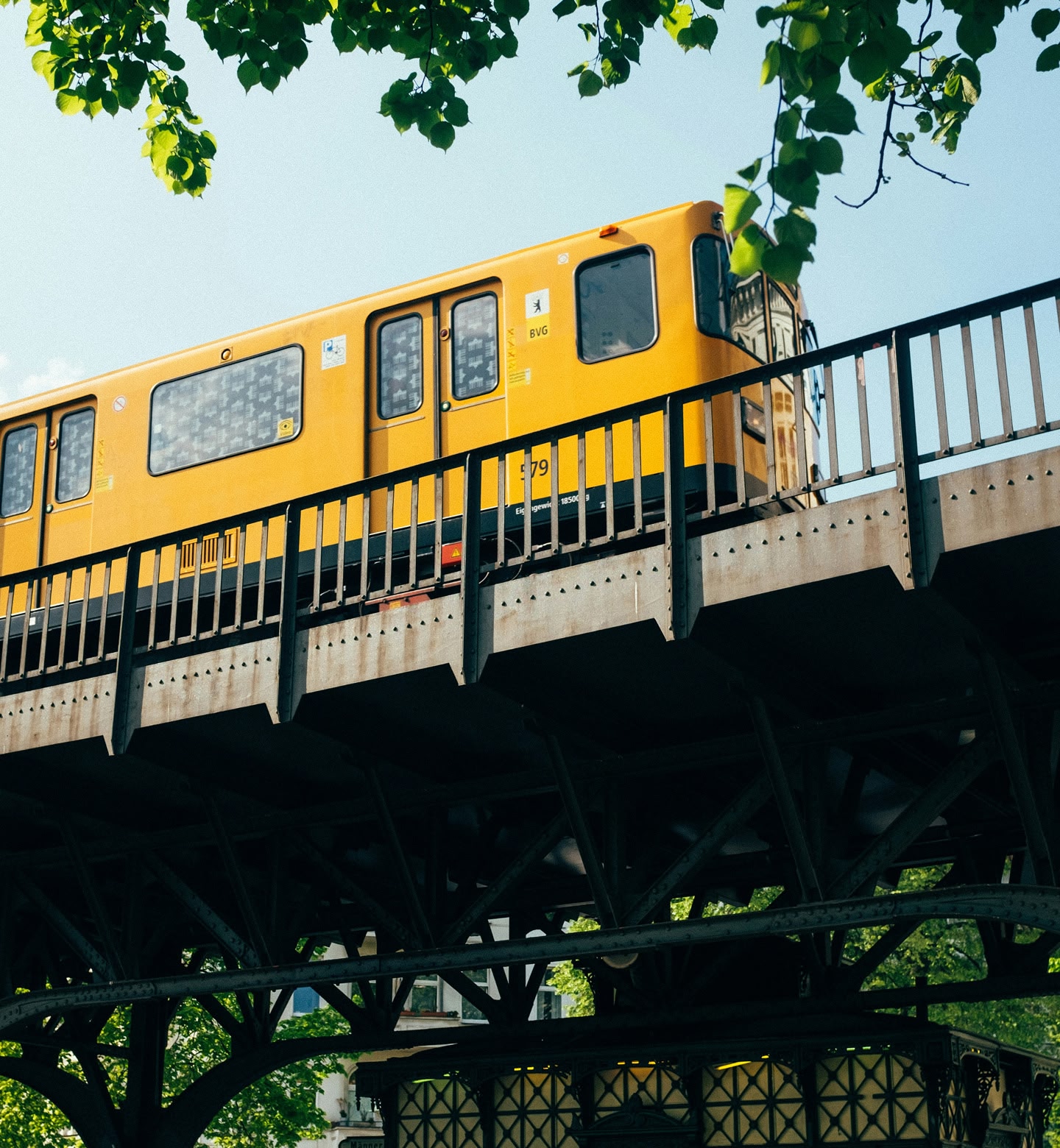 A yellow train passes overhead in Berlin, Germany.