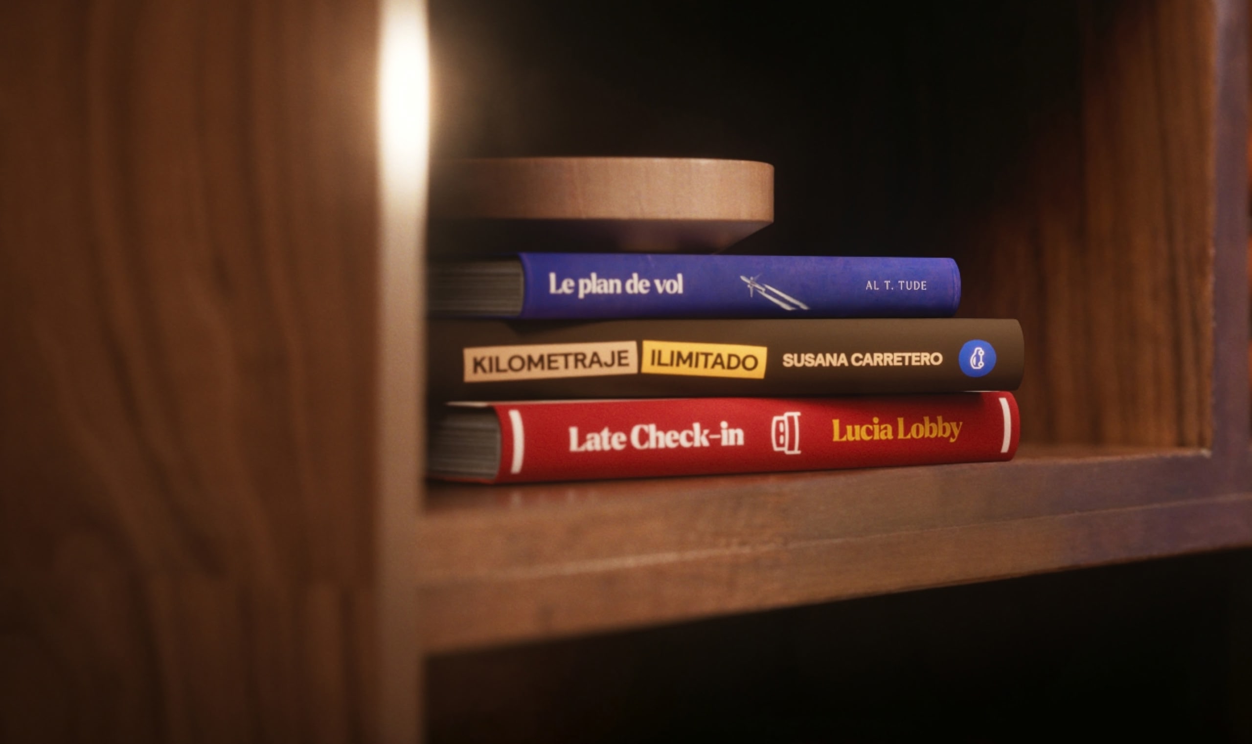 Tres libros apilados uno encima del otro en un estante de madera marrón