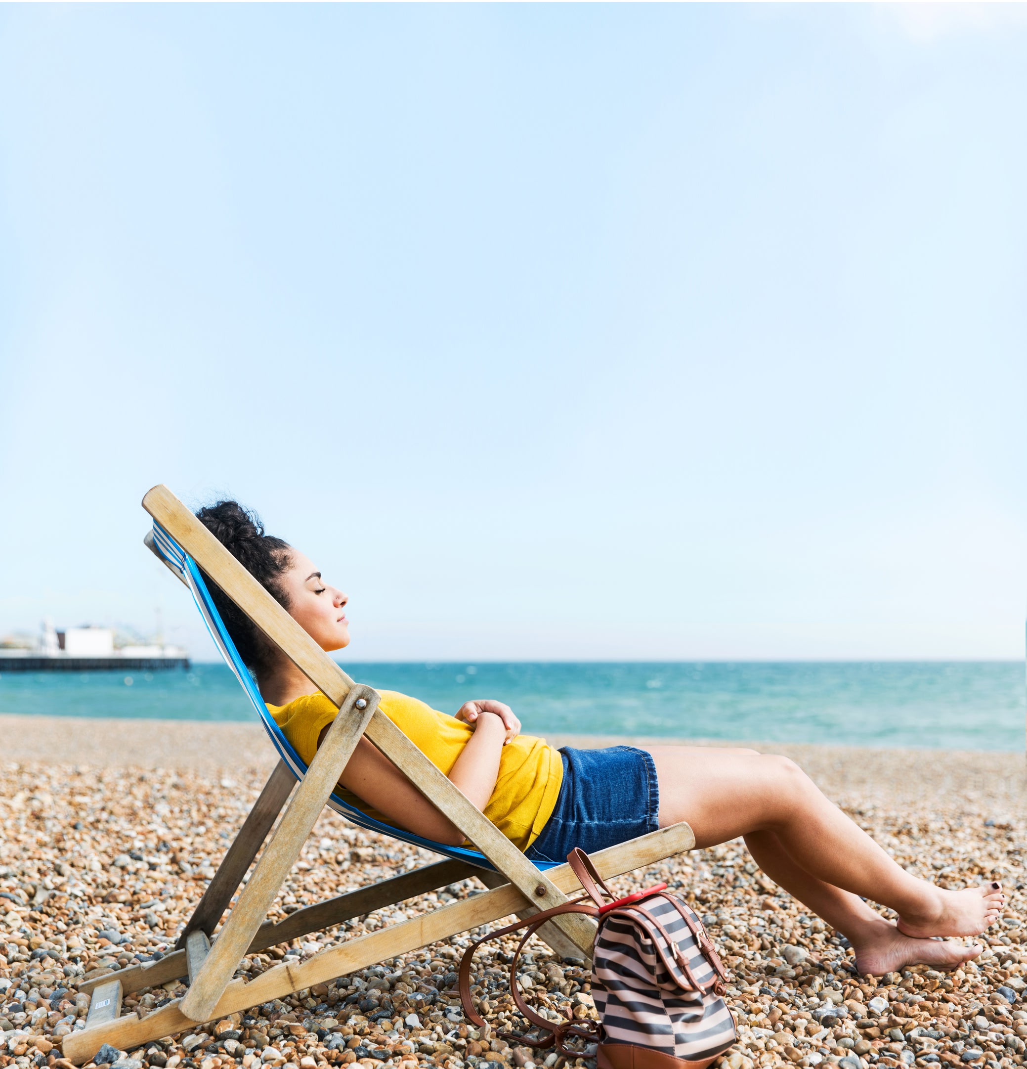 A photo of a woman sleeping in a deck chair on a beach