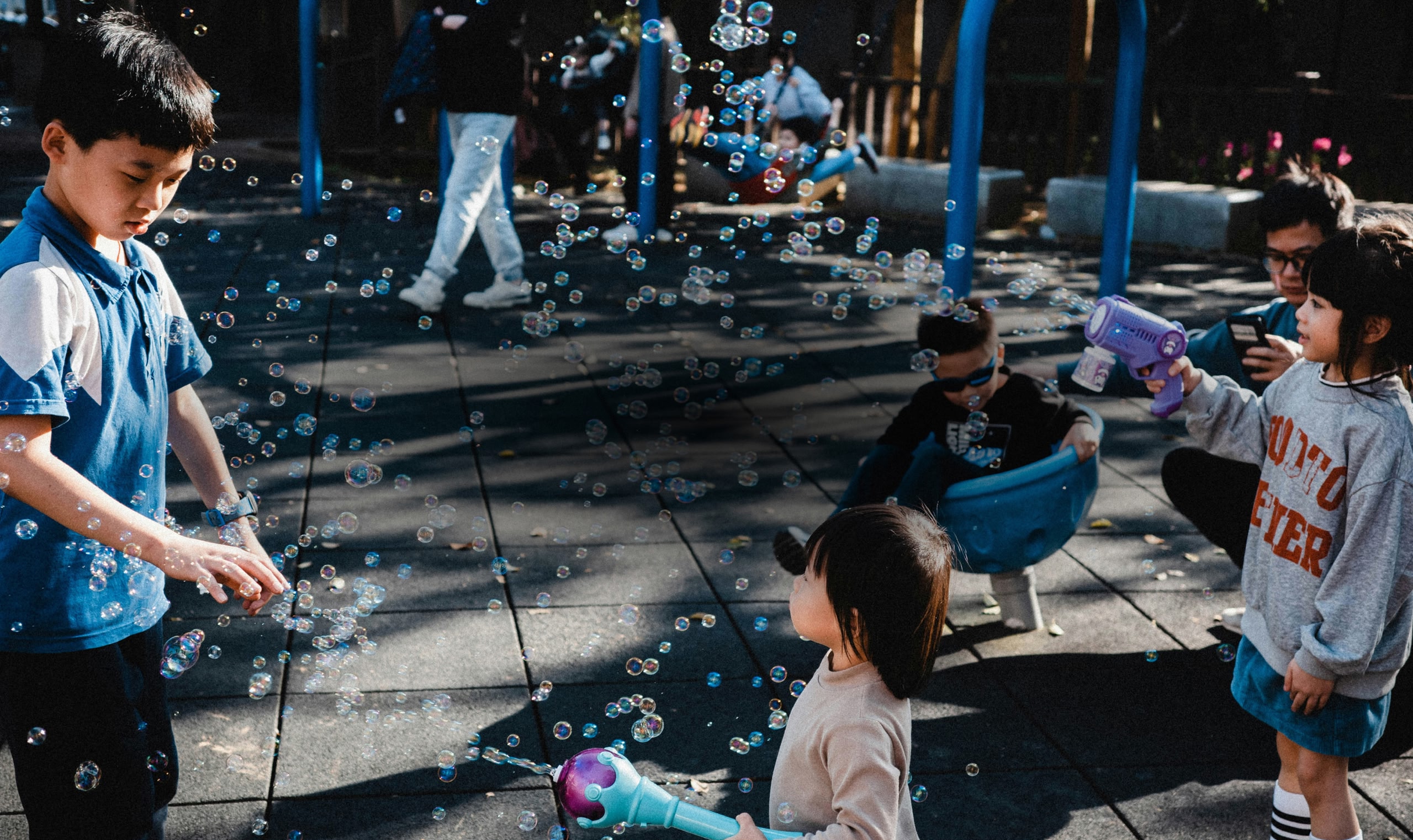 賑やかな遊び場で、子どもたちがバブルガンで遊んでいる。