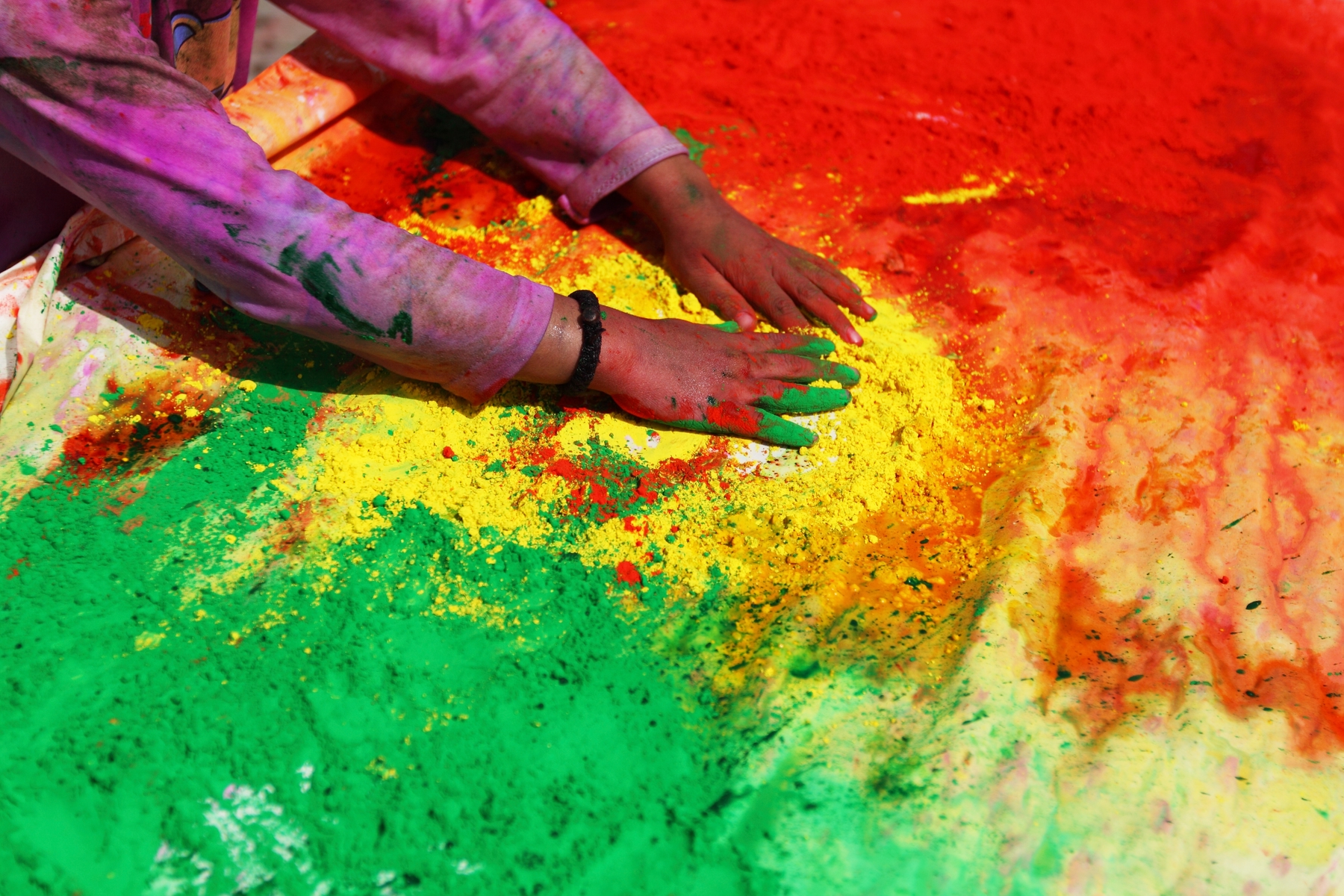 person playing with red, yellow, and green clay for Holi fest in India