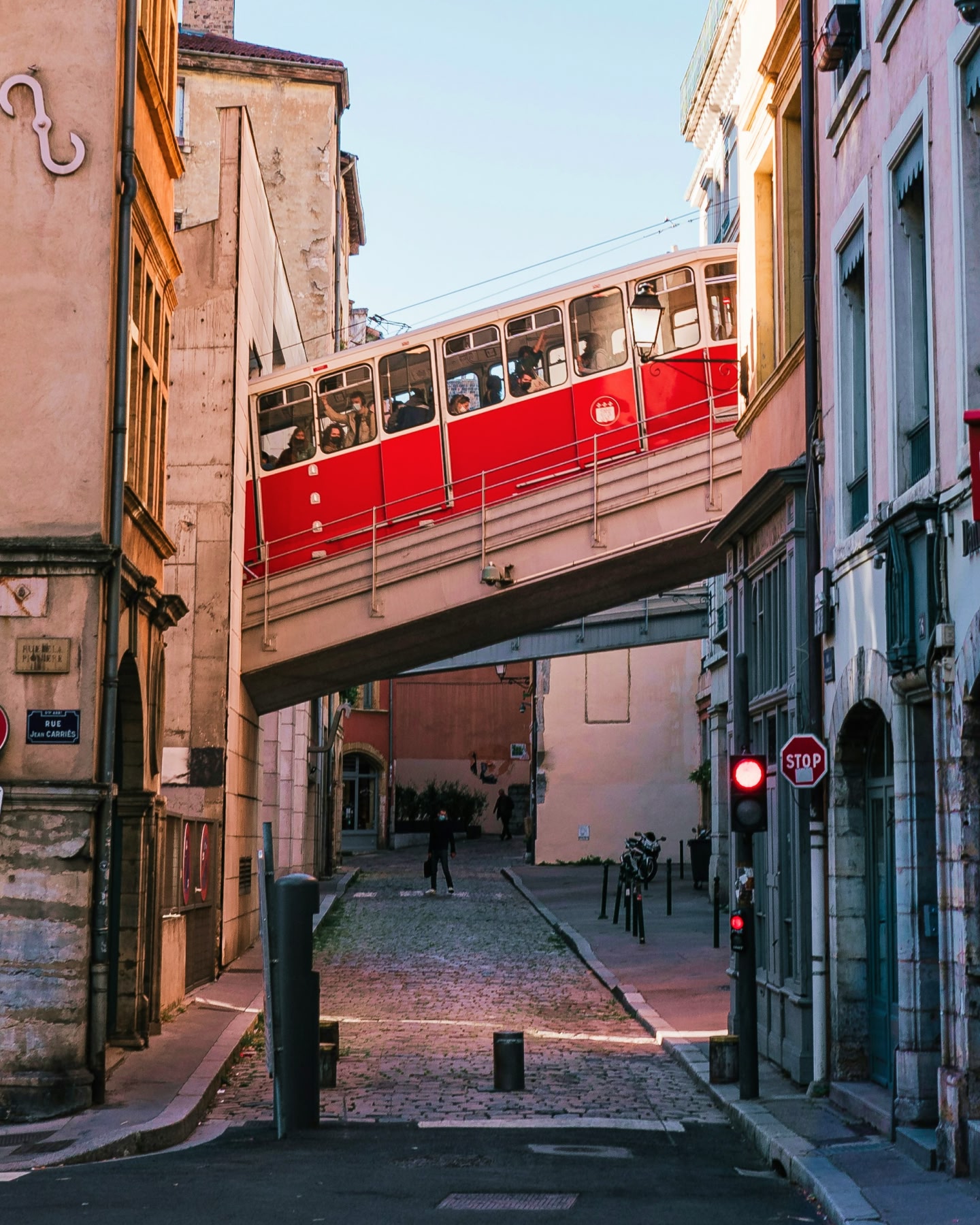 A red funicular train crossing a bridge above cobbled streets in Lyon, France.
