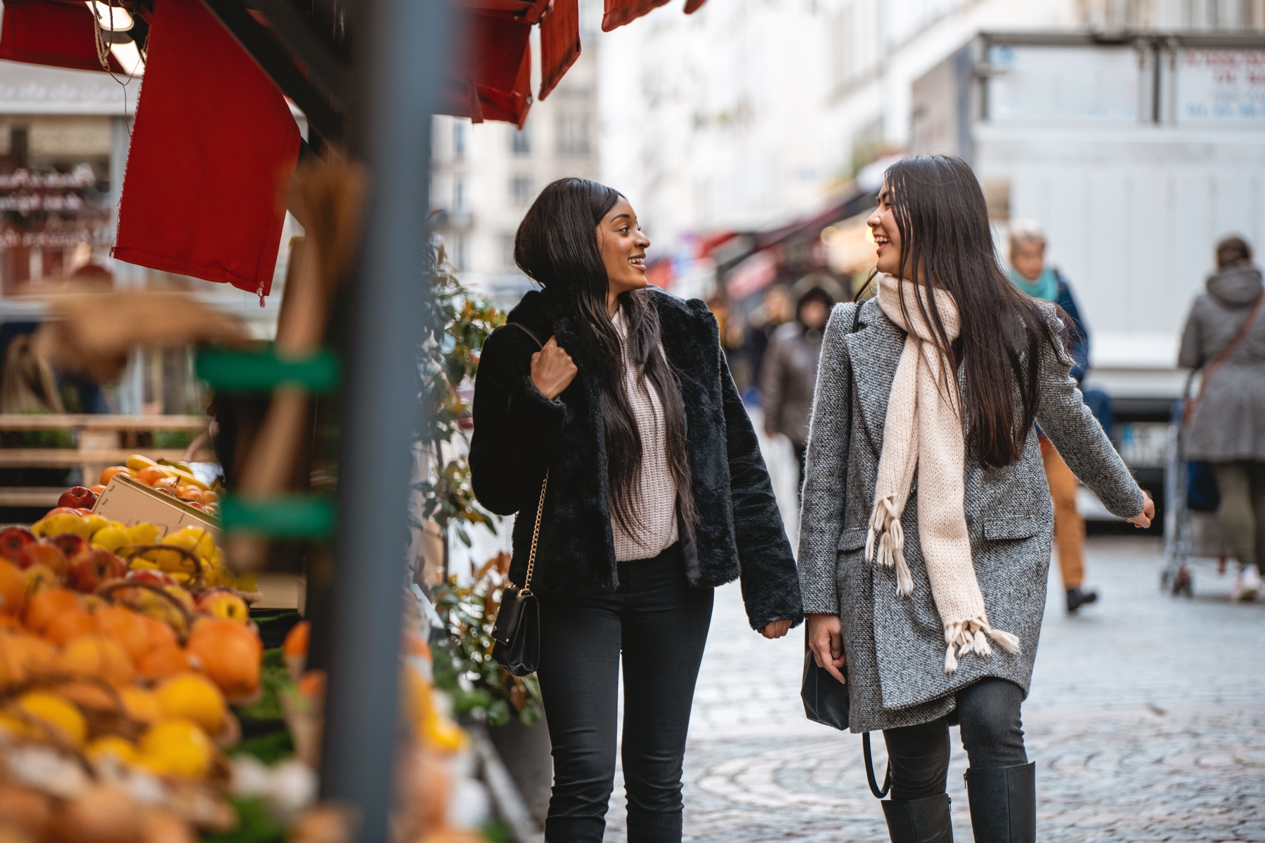 Duas mulheres passeando em uma feira de rua.