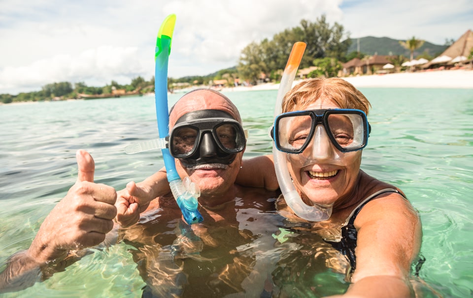 An older couple with snorkel gear on in the water.